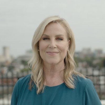 A woman in a blue dress is smiling for the camera.
