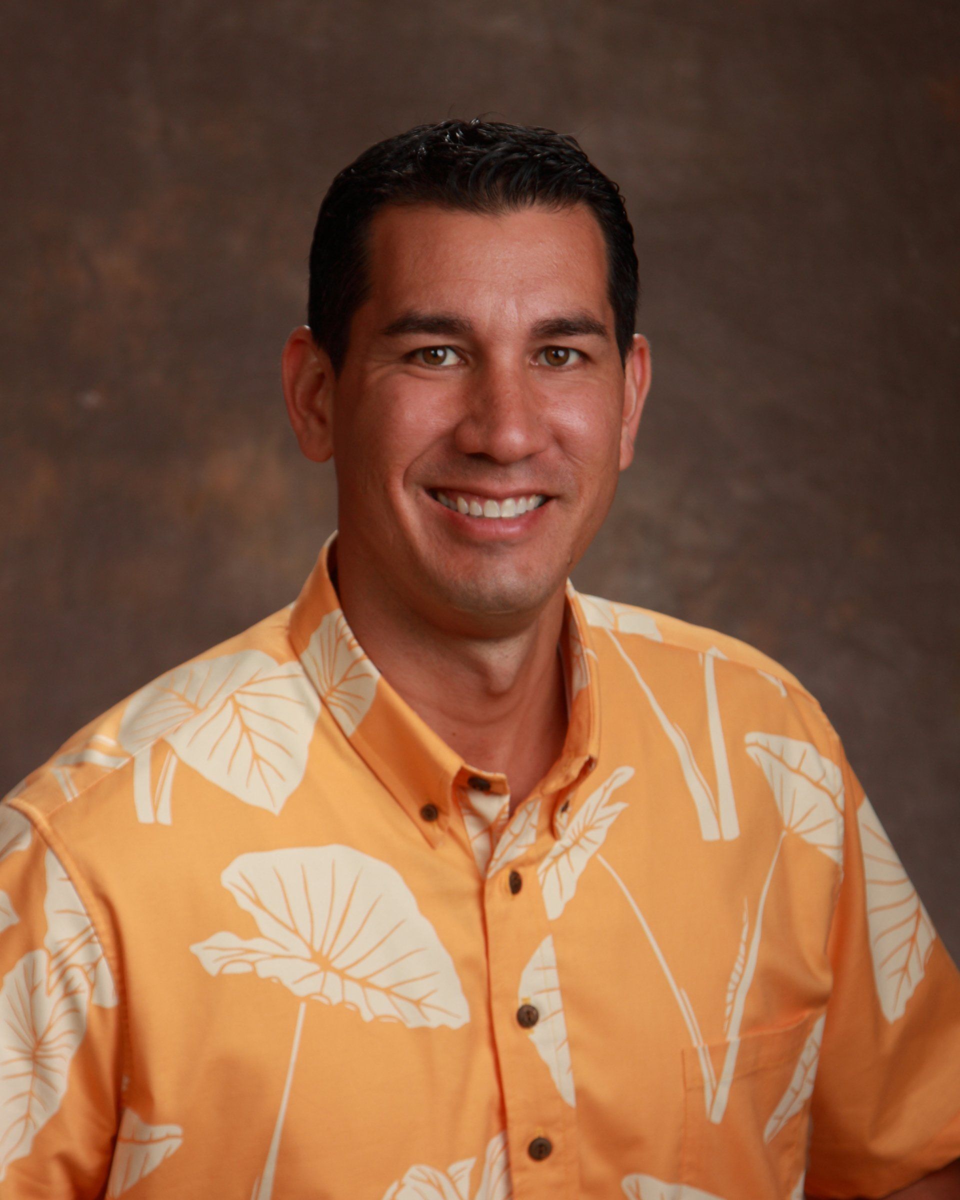 A man wearing an orange shirt with white leaves on it