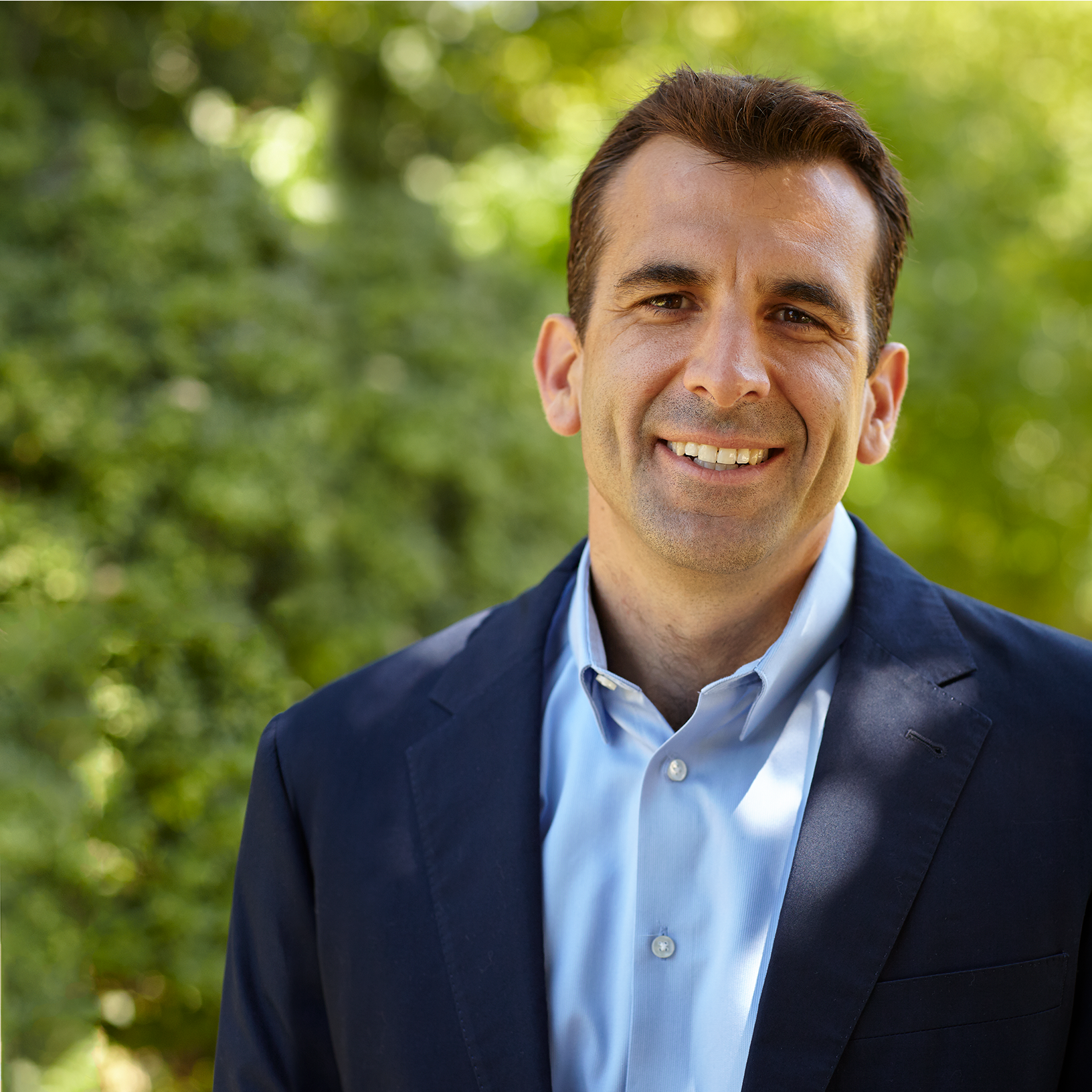 A man in a suit and blue shirt smiles for the camera