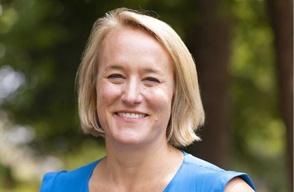 A woman in a blue shirt is smiling for the camera.