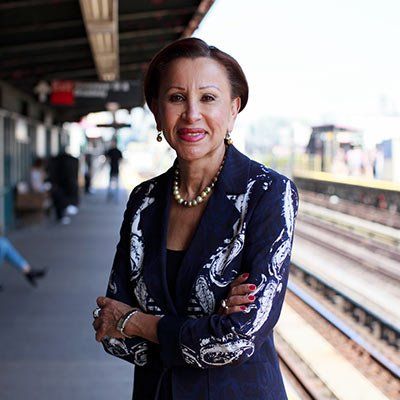 A woman is standing on a train platform with her arms crossed