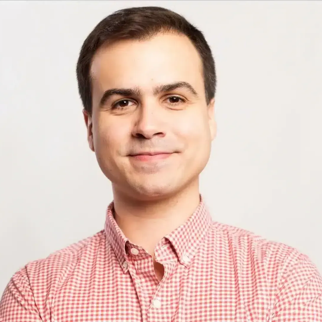 A man in a red and white checkered shirt is smiling for the camera