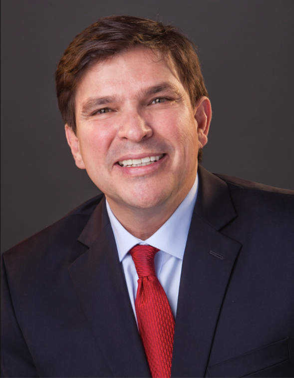 A man in a suit and tie is smiling for the camera