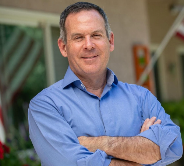 A man in a blue shirt is standing with his arms crossed
