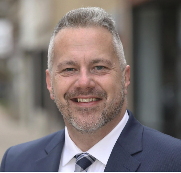 A man in a suit and tie is smiling for the camera