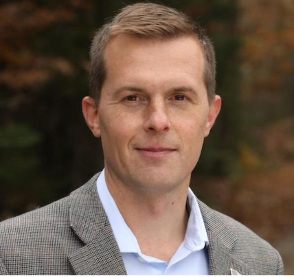 A man in a suit and blue shirt is smiling for the camera