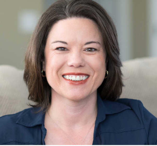 A woman in a blue shirt is smiling for the camera