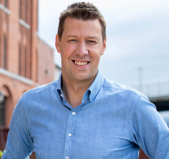 A man in a blue shirt is smiling for the camera