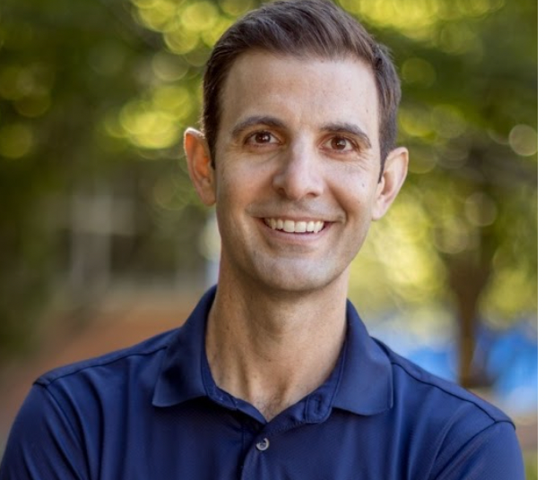 A man in a blue shirt is smiling for the camera.