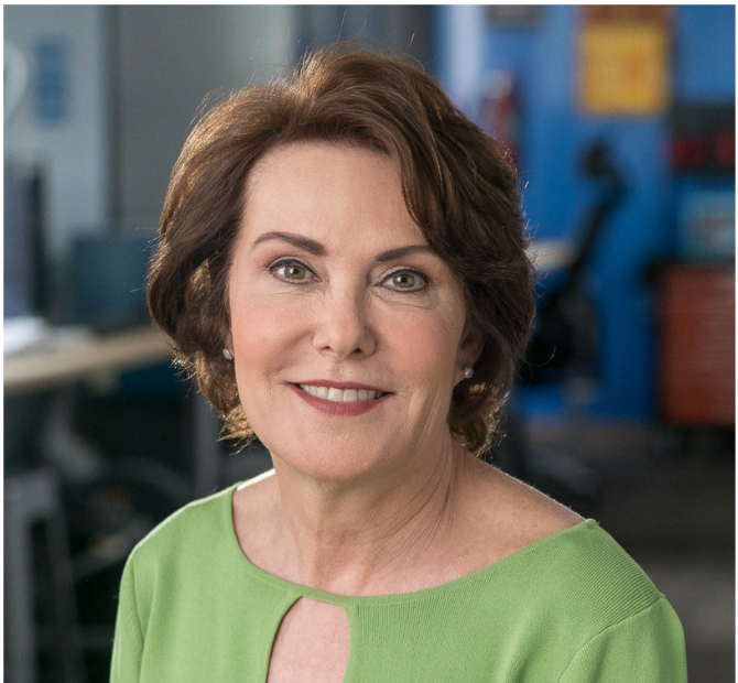A woman in a green shirt is smiling for the camera.