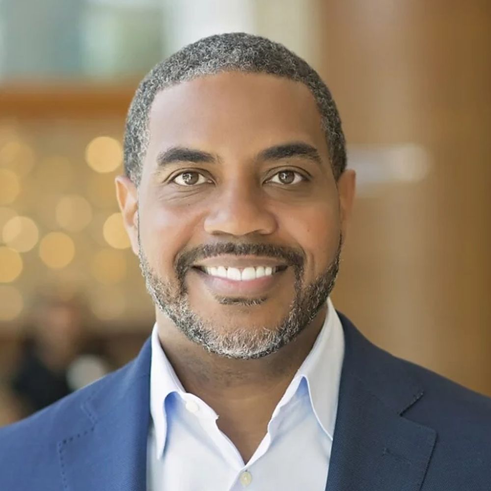 A man with a beard and a blue suit is smiling for the camera.