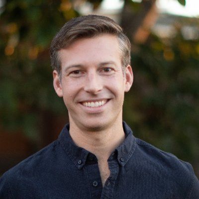 A man in a blue shirt is smiling for the camera.