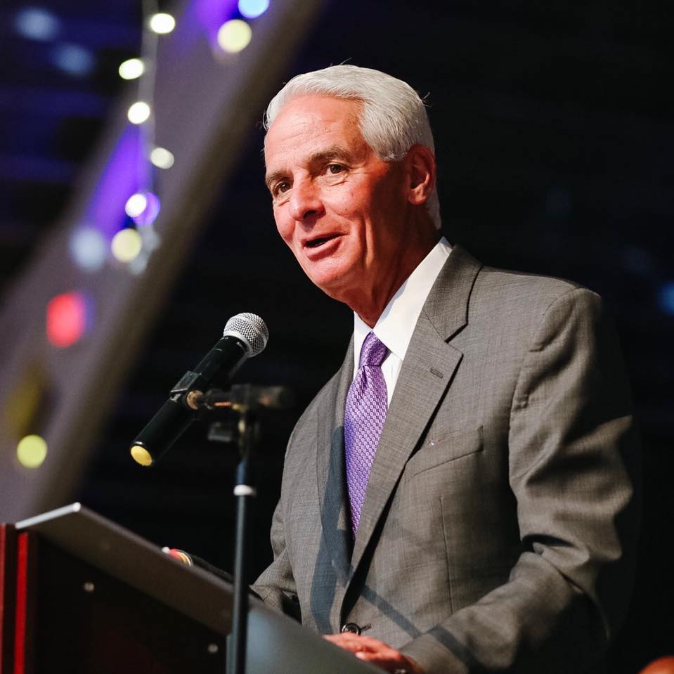 A man in a suit and tie is speaking into a microphone