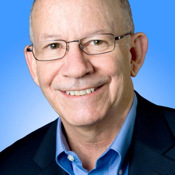 A man wearing glasses and a blue shirt smiles for the camera