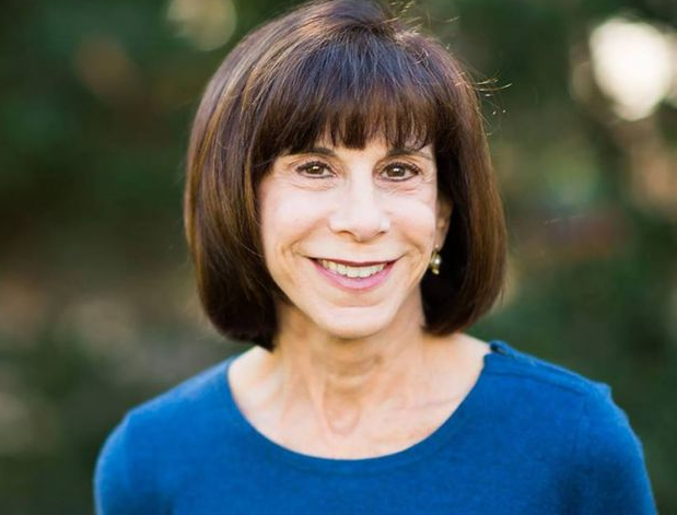 A woman in a blue shirt is smiling for the camera.