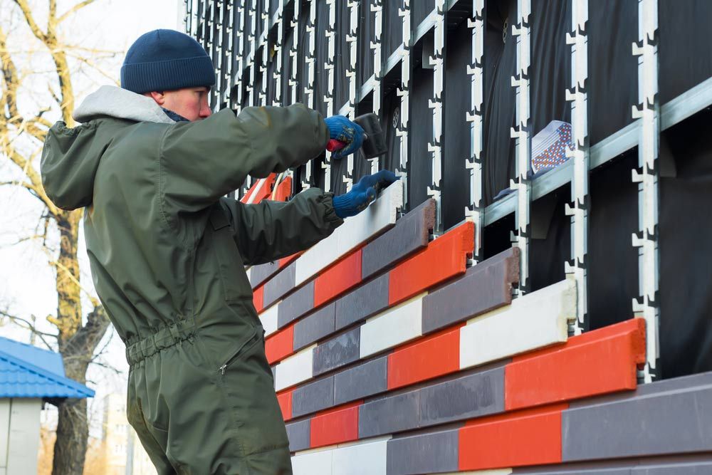 Worker Wall Cladding Stone The Worker Makes Facing And Warming Of An External Wall Of Building — High-Quality Building Supplies in Tamworth, NSW
