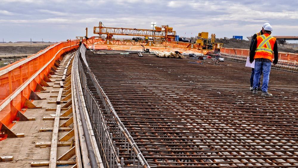 Workers On Bridge Deck Panels With Reinforcing Steel Bars On Top Of Concrete Girders Prior To Pouring Concrete Over Reinforcing Steel — Selling Quality Building Products in Tamworth, NSW