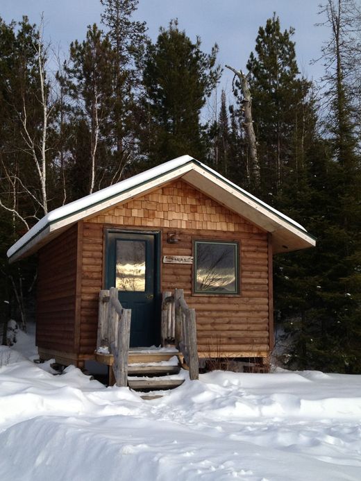 A small wooden cabin in the middle of a snowy forest