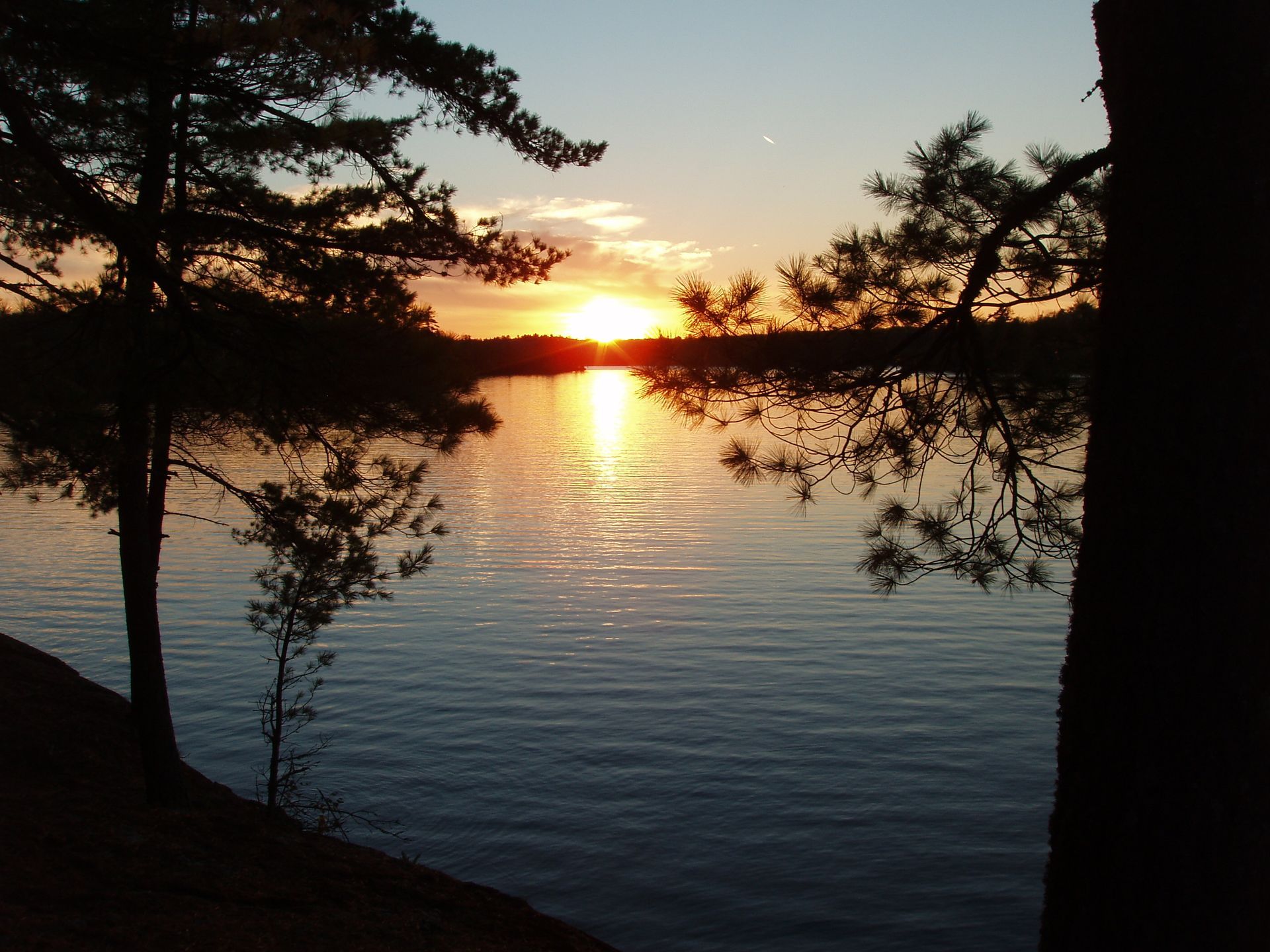 A sunset over a lake with trees in the foreground