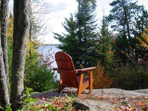 A wooden chair sits on a rock overlooking a lake