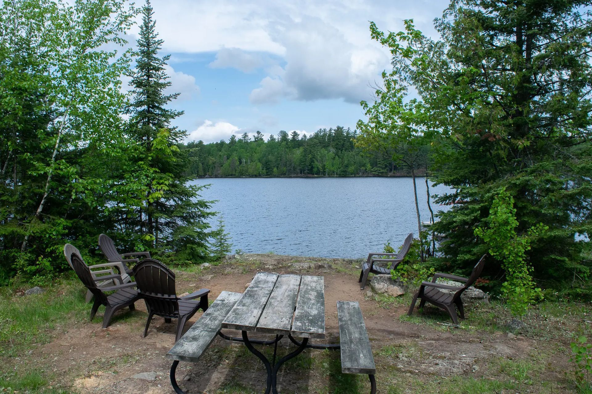 A picnic table with chairs in front of a lake
