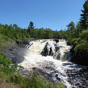 A waterfall is surrounded by trees and rocks in the middle of a forest.