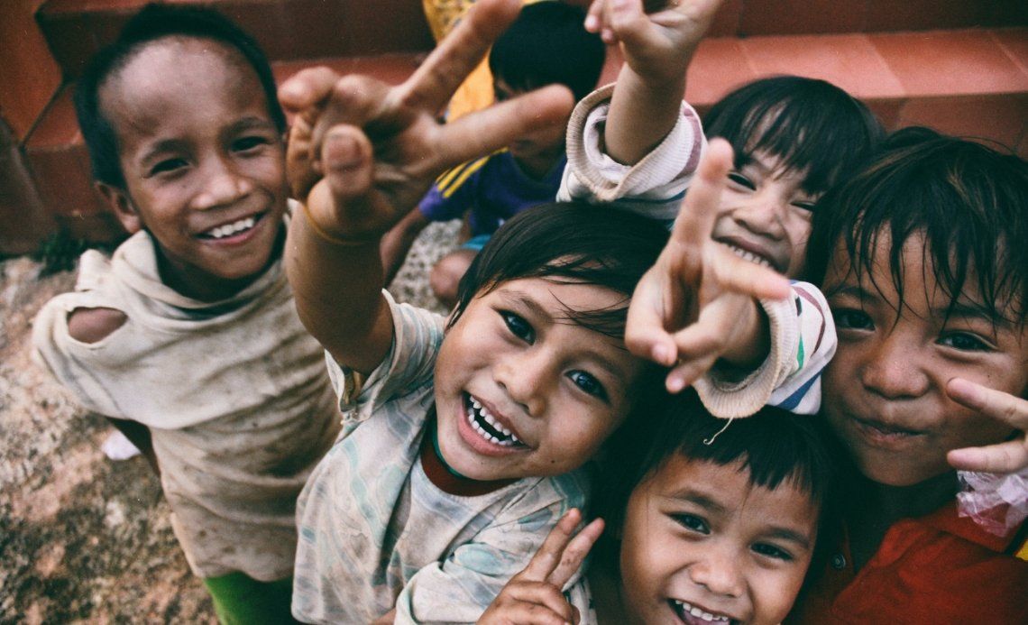 A group of children are making peace signs with their hands.