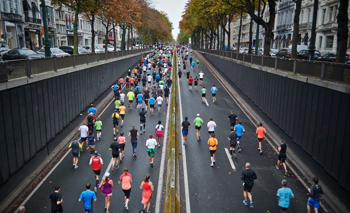 A large group of people are running a marathon on a city street.