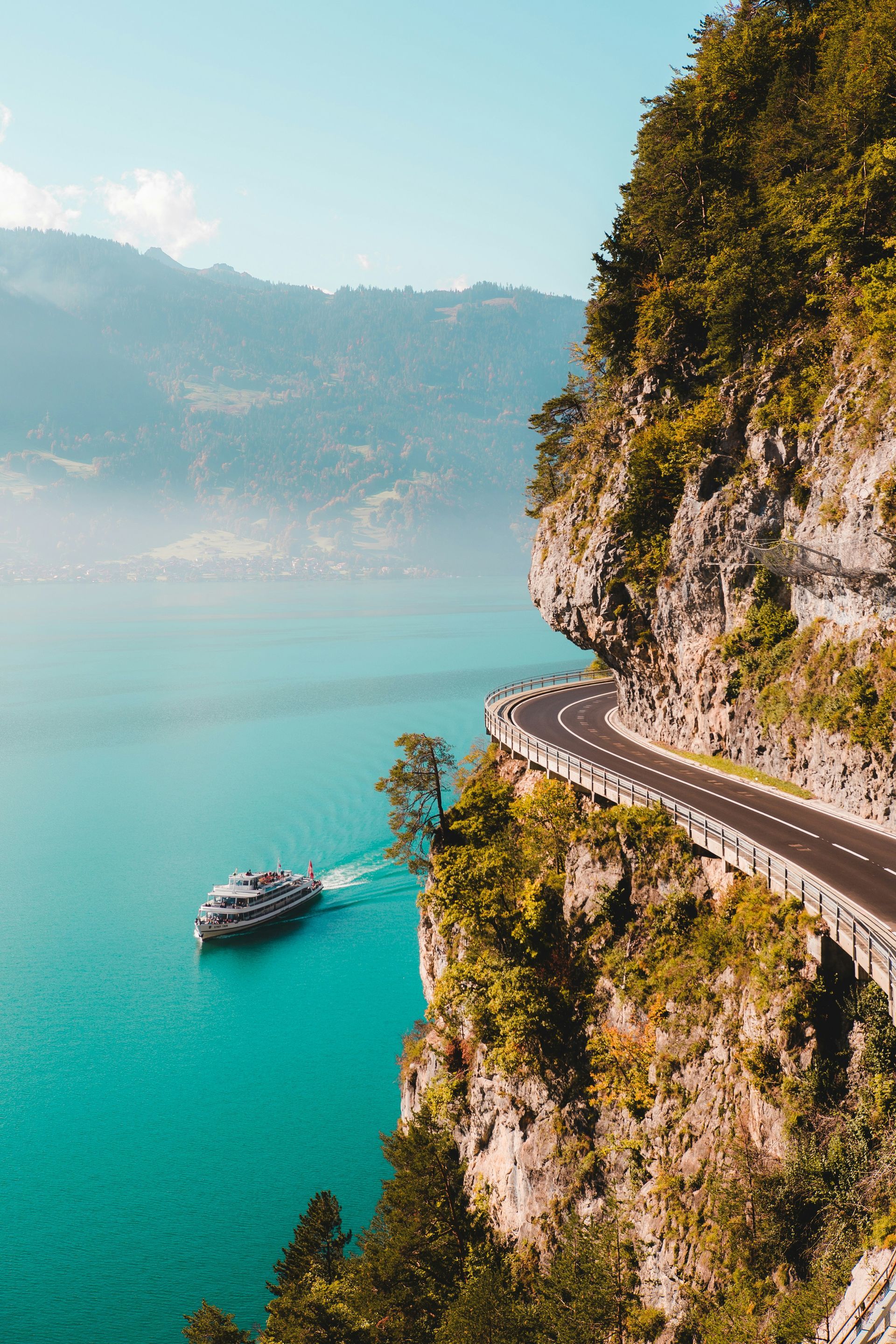 A boat is floating on top of a lake next to a road.