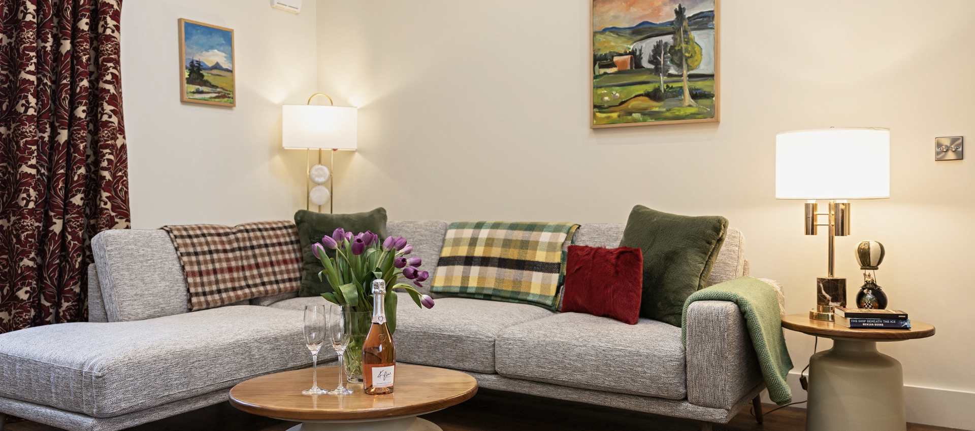 A living room with a couch , table , lamp and painting on the wall.