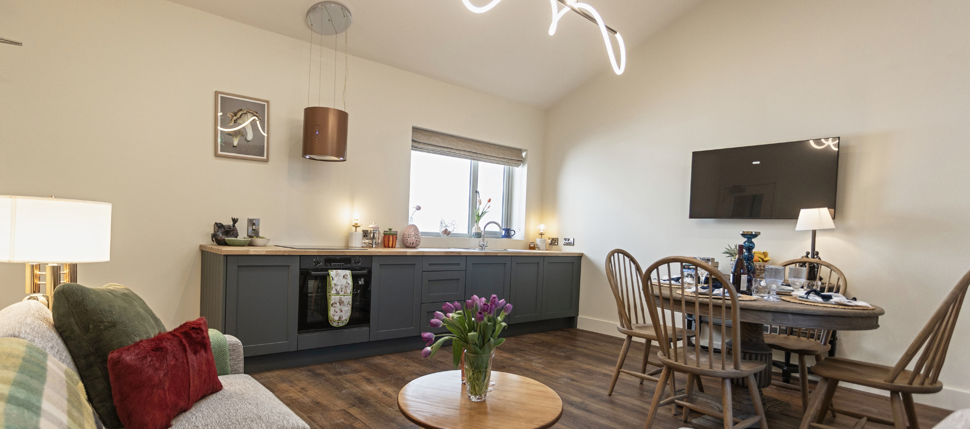 A living room with a couch , table , chairs and a flat screen tv.