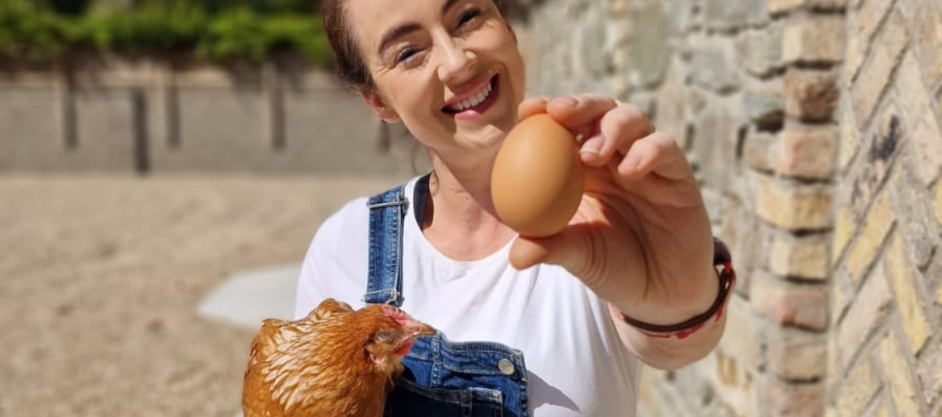 A woman is holding a chicken and an egg in her hands.
