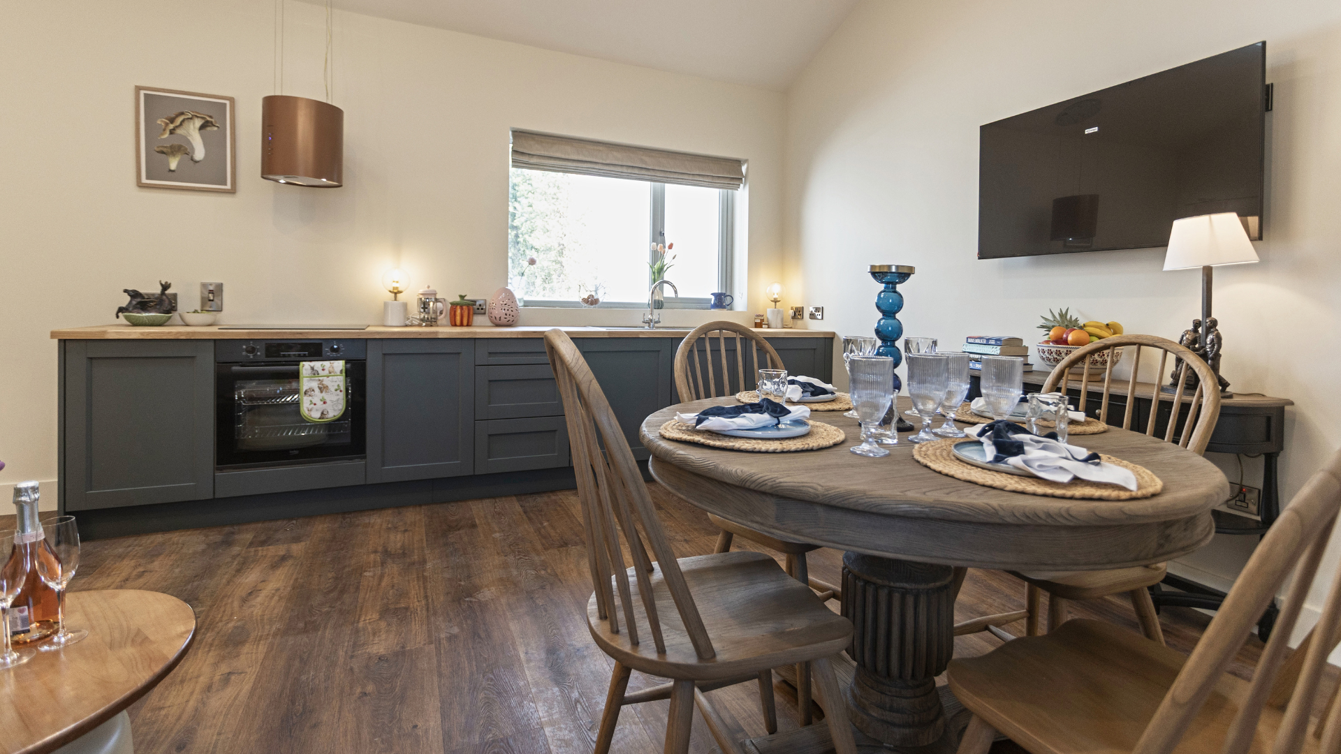 A kitchen with a table and chairs and a flat screen tv.
