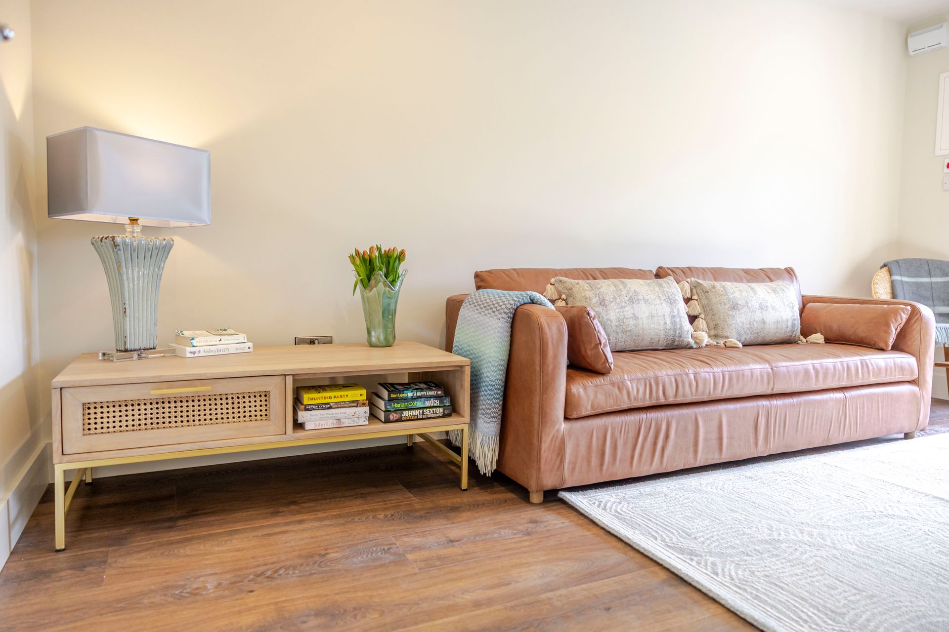A living room with a couch , table , lamp and rug.