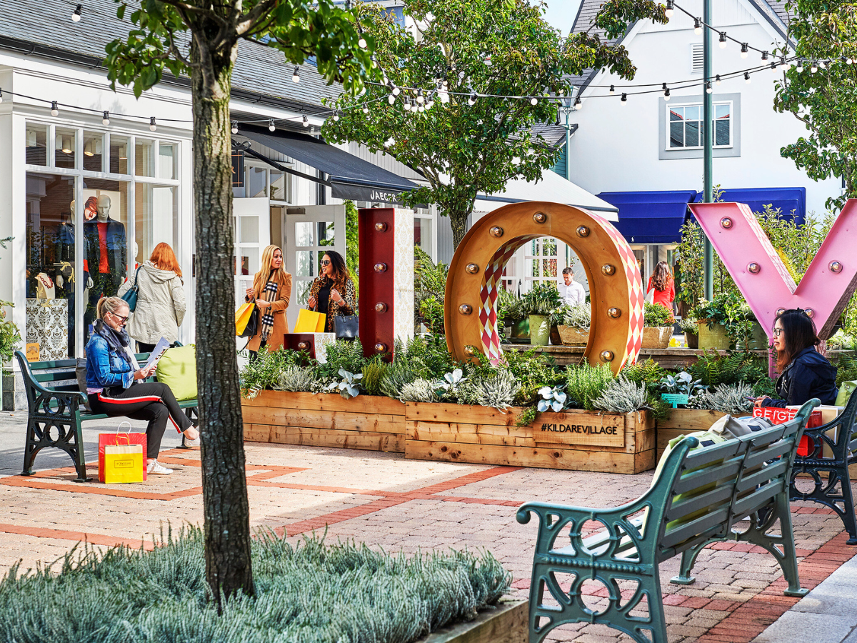 A group of people are sitting on benches in front of a store.