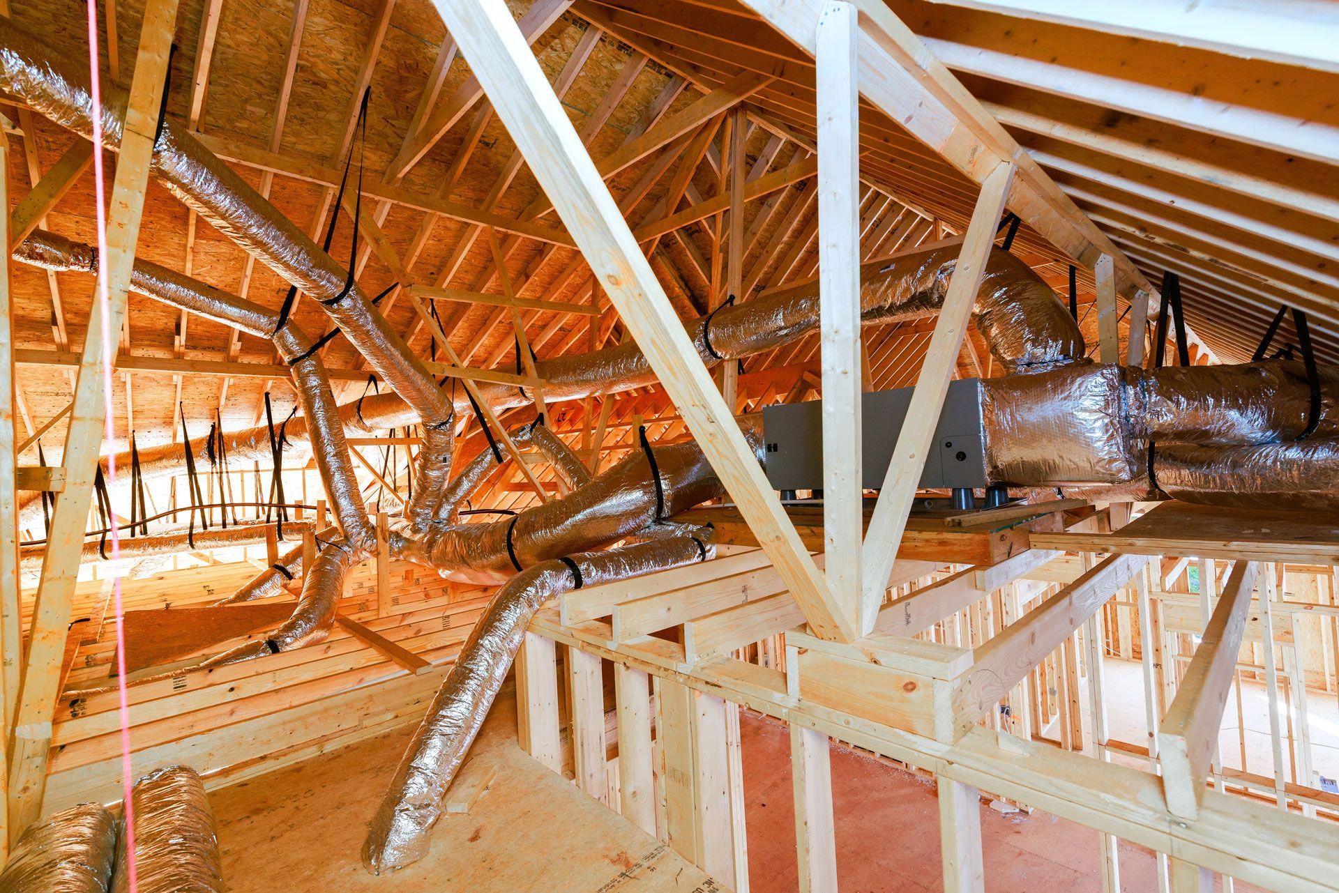 Interior of a wooden roof structure under construction, with exposed beams, trusses, and bright daylight