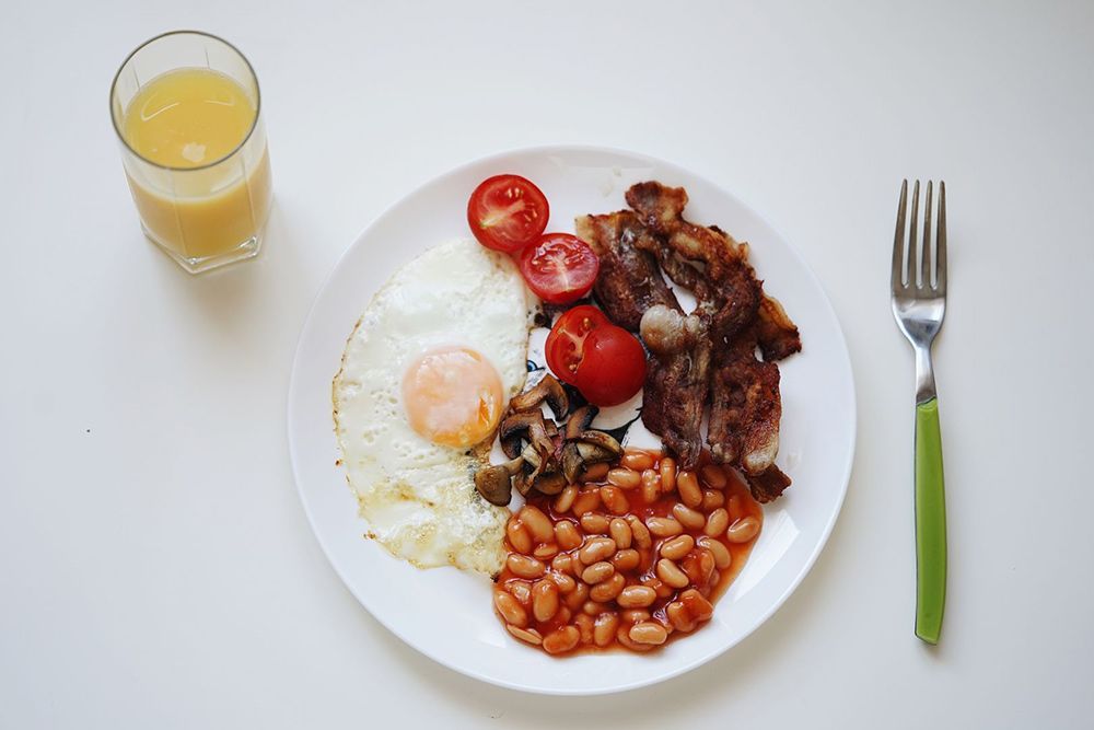 A Plate of Food With Eggs, Beans, Bacon, Tomatoes and a Glass of Orange Juice — Lakeview Luxury Retreat in Canobolas, NSW