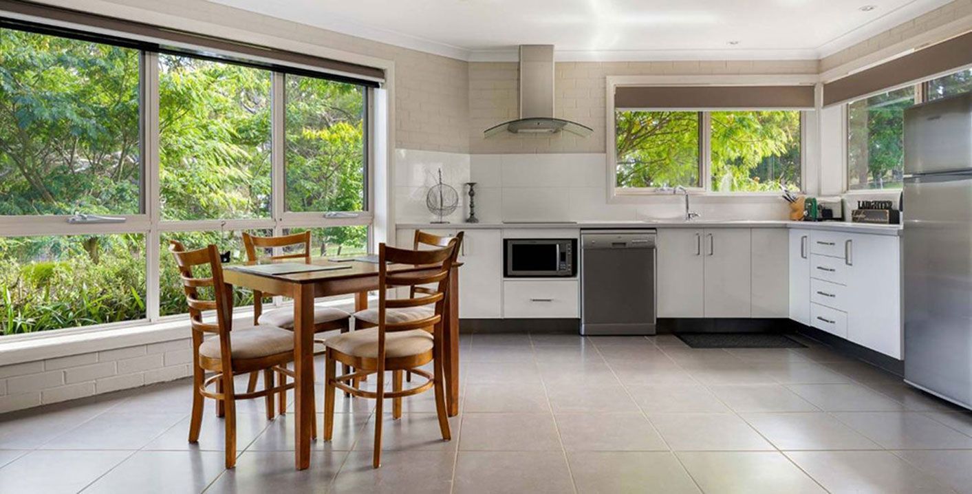 A Kitchen With a Table and Chairs in It and a Lot of Windows — Lakeview Luxury Retreat in Canobolas, NSW