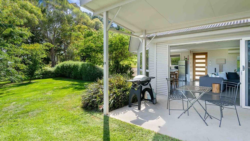 A Patio With a Table and Chairs and a Grill in the Backyard of a House — Lakeview Luxury Retreat in Canobolas, NSW