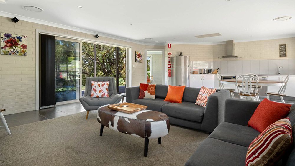 A Living Room With a Couch, Chair, Coffee Table and Ottoman — Lakeview Luxury Retreat in Canobolas, NSW