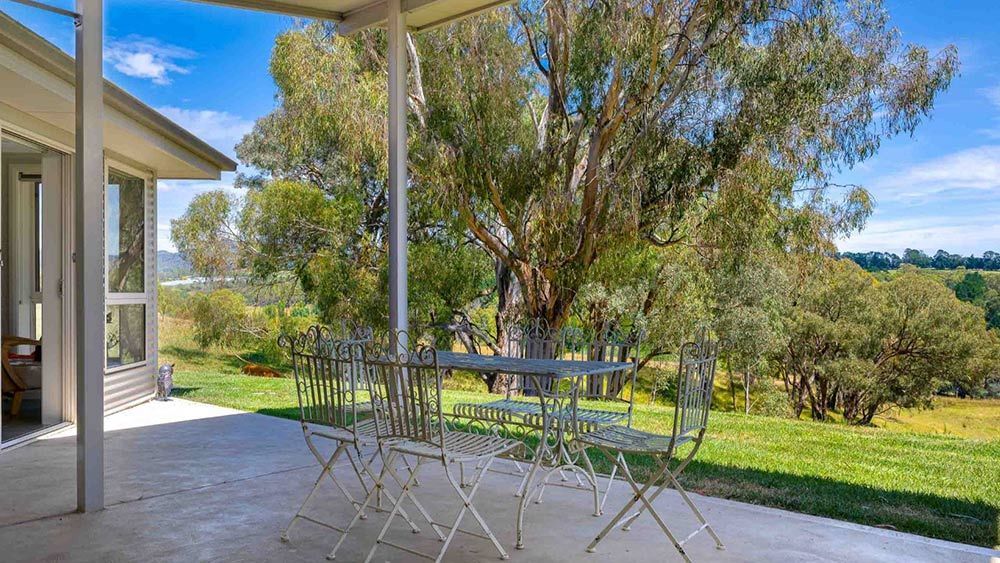 There is a Table and Chairs on the Porch of a House — Lakeview Luxury Retreat in Canobolas, NSW