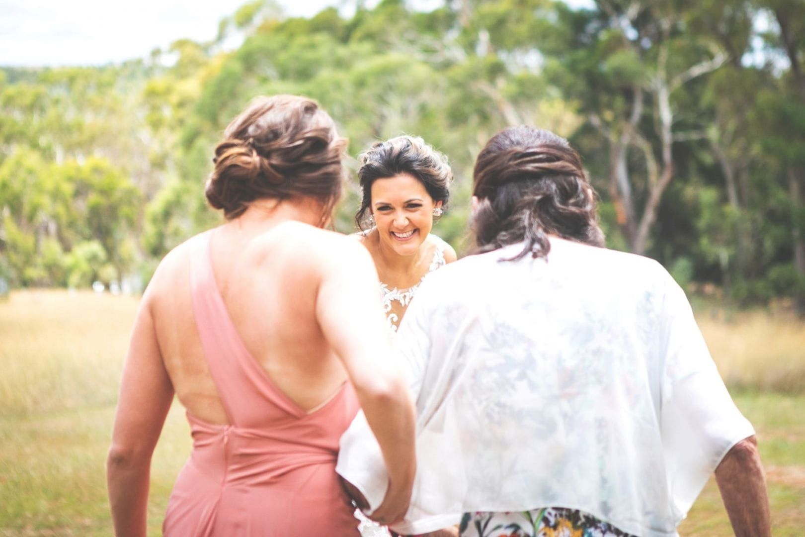 A Bride and Her Bridesmaids Are Standing in a Field Holding Hands — Lakeview Luxury Retreat in Canobolas, NSW