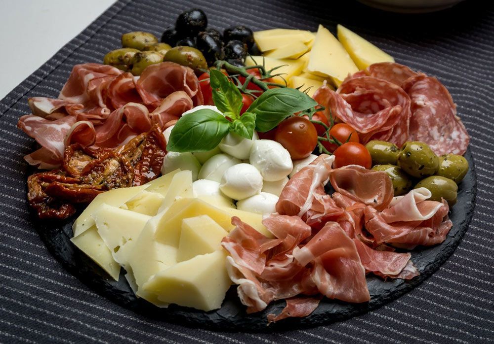 A Plate of Meat, Cheese, Olives and Tomatoes on a Table — Lakeview Luxury Retreat in Canobolas, NSW