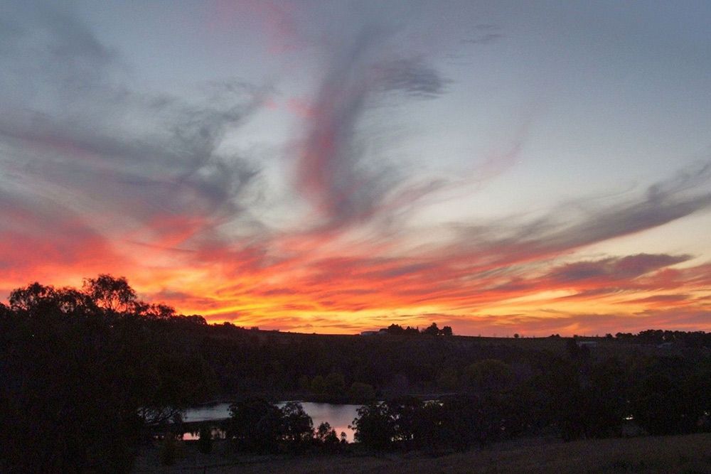 A Sunset Over a Lake With Trees in the Foreground — Lakeview Luxury Retreat in Canobolas, NSW