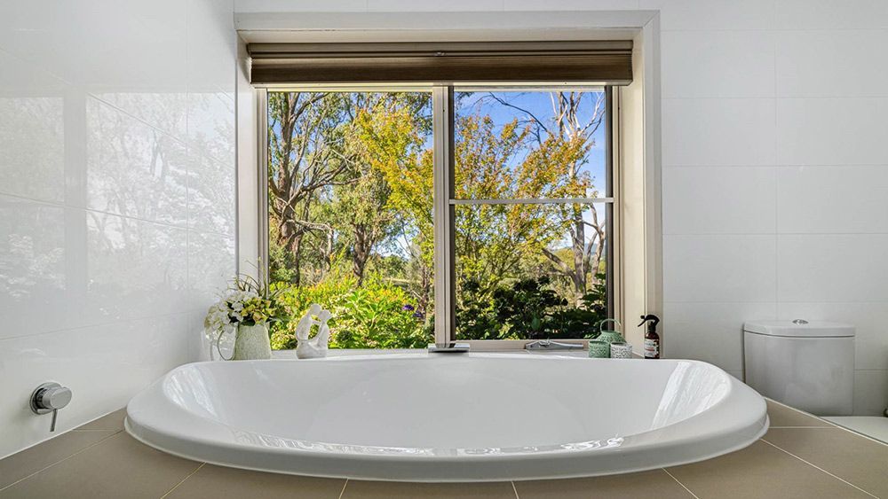 There is a Large Bathtub in the Bathroom With a Large Window — Lakeview Luxury Retreat in Canobolas, NSW