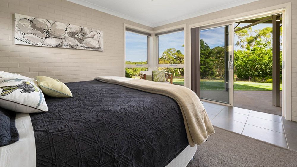 A Bedroom With a Bed, Sliding Glass Doors, and a Painting on the Wall — Lakeview Luxury Retreat in Canobolas, NSW