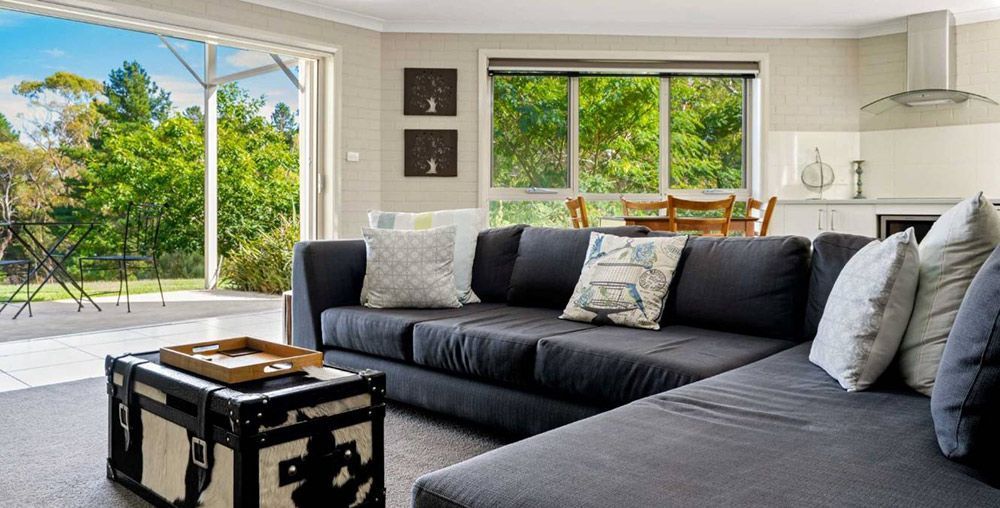 A Living Room With a Couch, Coffee Table, and Sliding Glass Doors — Lakeview Luxury Retreat in Canobolas, NSW