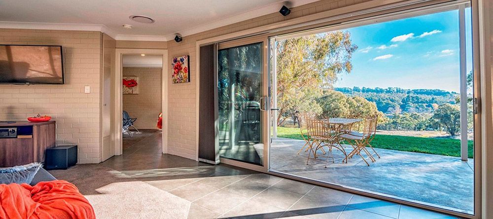 A Living Room With a Large Sliding Glass Door Leading to a Patio — Lakeview Luxury Retreat in Canobolas, NSW