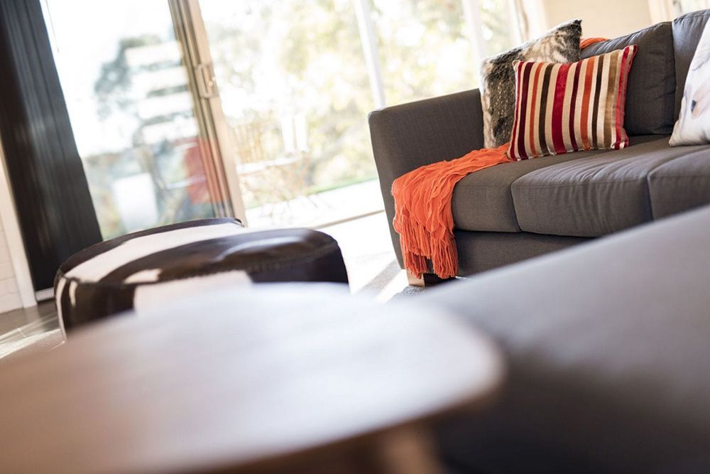 A Living Room With a Couch, Ottoman, and Table — Lakeview Luxury Retreat in Canobolas, NSW