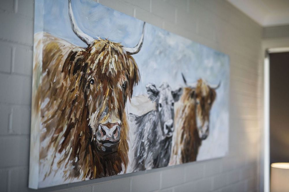 A Painting of Three Cows With Horns is Hanging on a Wall — Lakeview Luxury Retreat in Canobolas, NSW
